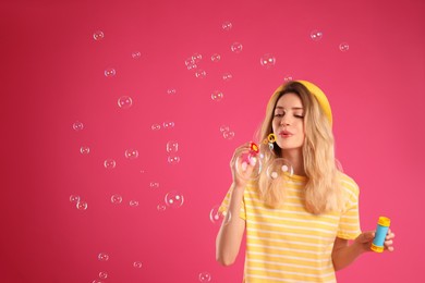 Young woman blowing soap bubbles on pink background, space for text Photo of Young woman blowing soap bubbles on pink background, space for text
