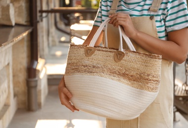 Photo of Young woman with stylish straw bag outdoors, closeup