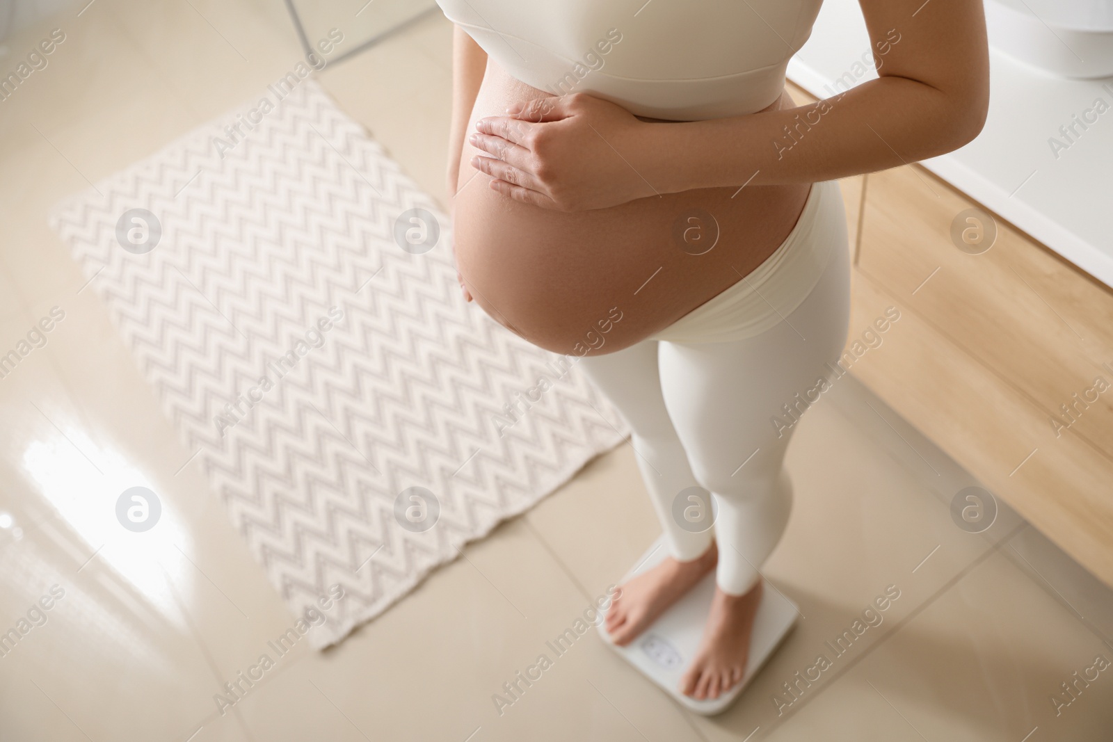 Pregnant woman standing on scales at home, closeup Photo of Pregnant woman standing on scales at home, closeup