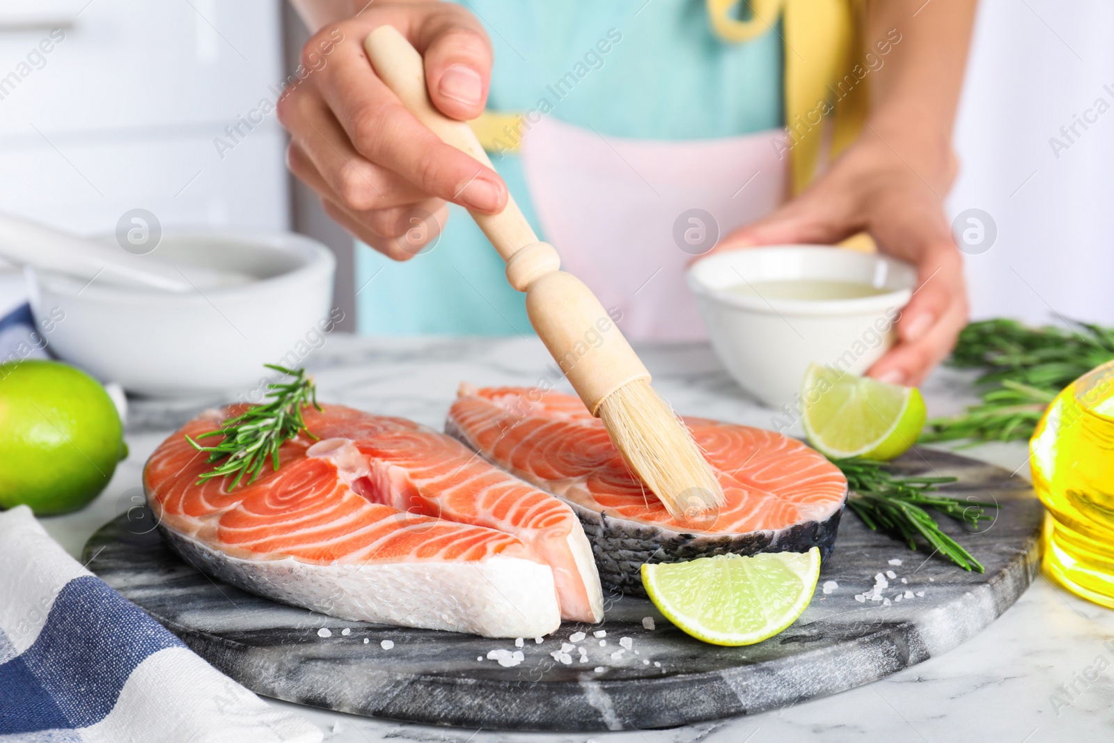 Woman marinating fresh raw salmon at table, closeup. Fish delicacy Photo of Woman marinating fresh raw salmon at table, closeup. Fish delicacy