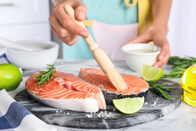 Woman marinating fresh raw salmon at table, closeup. Fish delicacy Photo of Woman marinating fresh raw salmon at table, closeup. Fish delicacy