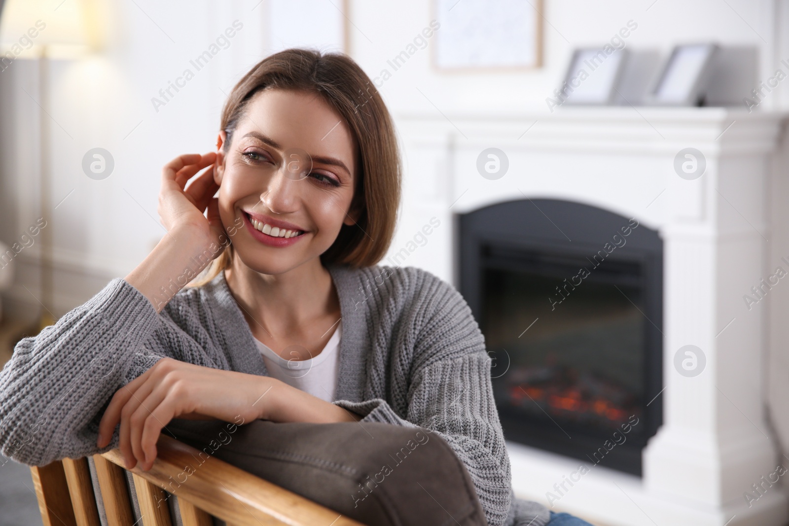 Young woman resting near fireplace at home, space for text Photo of Young woman resting near fireplace at home, space for text