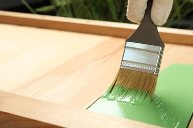 Worker applying green paint onto wooden surface, closeup. Space for text Photo of Worker applying green paint onto wooden surface, closeup. Space for text