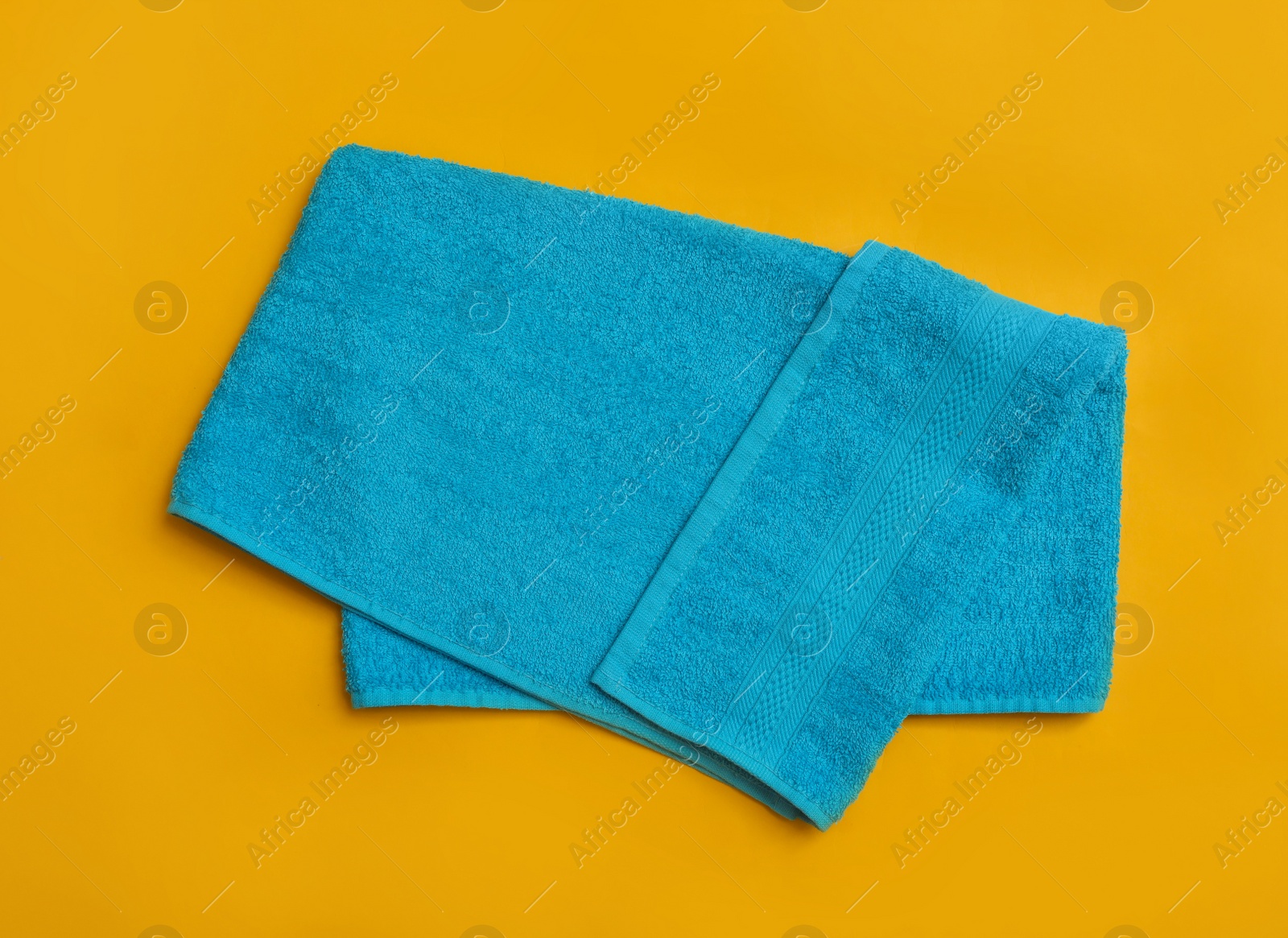 Folded light blue beach towel on yellow background, top view Photo of Folded light blue beach towel on yellow background, top view