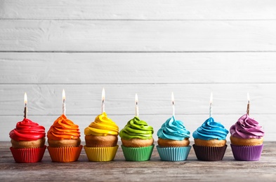 Delicious birthday cupcakes with burning candles on table Photo of Delicious birthday cupcakes with burning candles on table