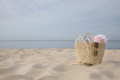 Beach bag with flip flops, towel and sunglasses on sandy seashore, space for text Photo of Beach bag with flip flops, towel and sunglasses on sandy seashore, space for text
