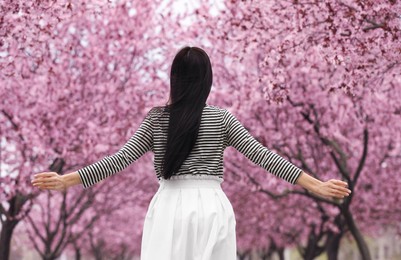 Young woman in park with blooming trees. Spring look Photo of Young woman in park with blooming trees. Spring look