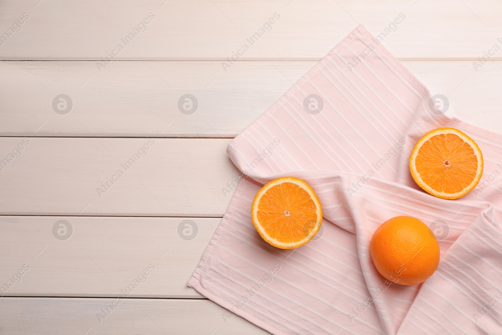 Pink kitchen towel with oranges on white wooden table, flat lay. Space for text Photo of Pink kitchen towel with oranges on white wooden table, flat lay. Space for text