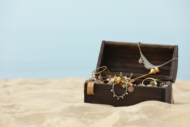 Open wooden chest with treasures on sandy beach, space for text Photo of Open wooden chest with treasures on sandy beach, space for text