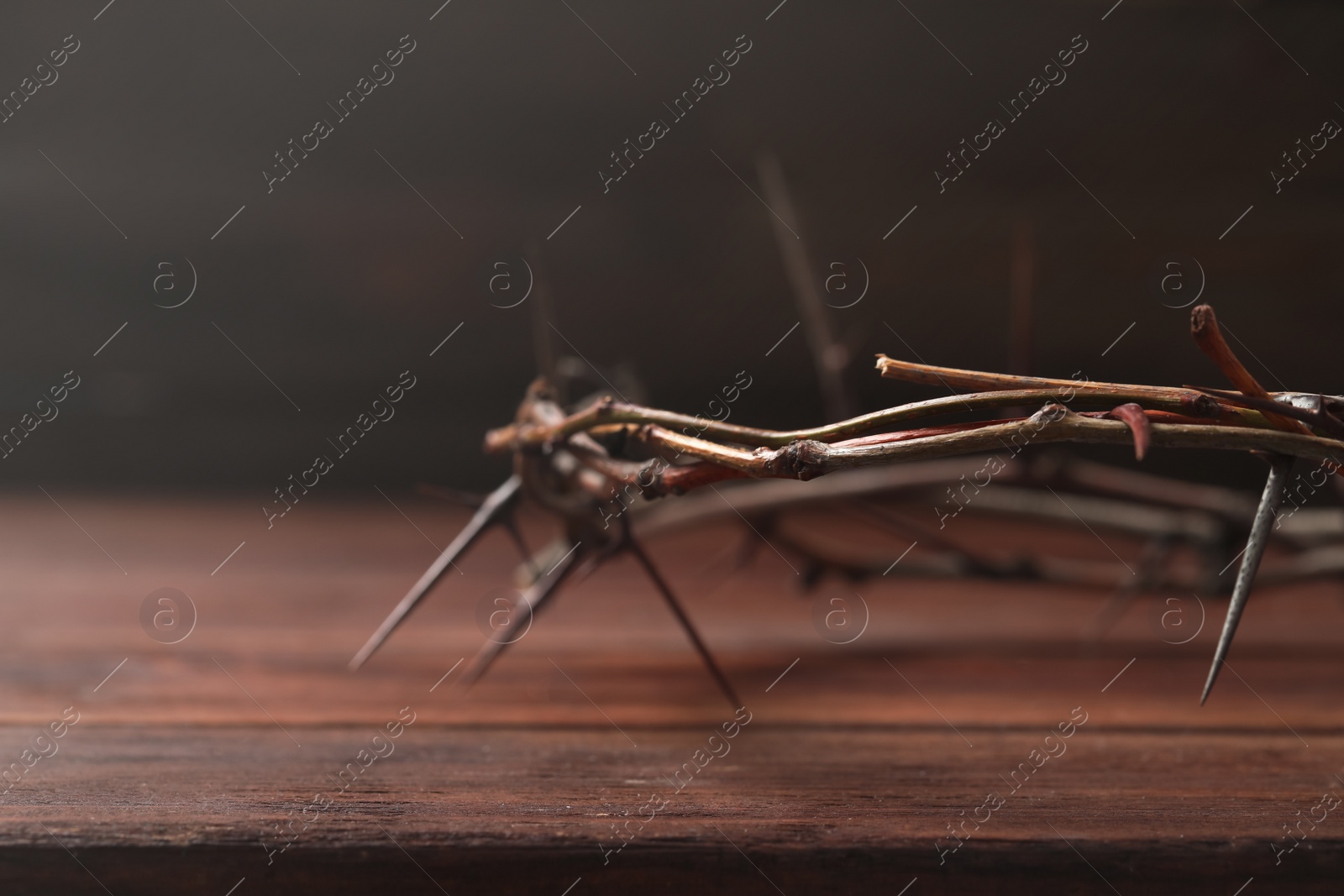 Photo of Crown of thorns on wooden table, closeup with space for text. Easter attribute