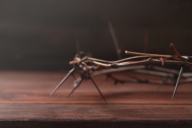 Photo of Crown of thorns on wooden table, closeup with space for text. Easter attribute