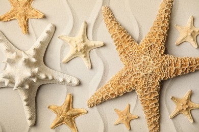 Beautiful sea stars on sand, flat lay Photo of Beautiful sea stars on sand, flat lay