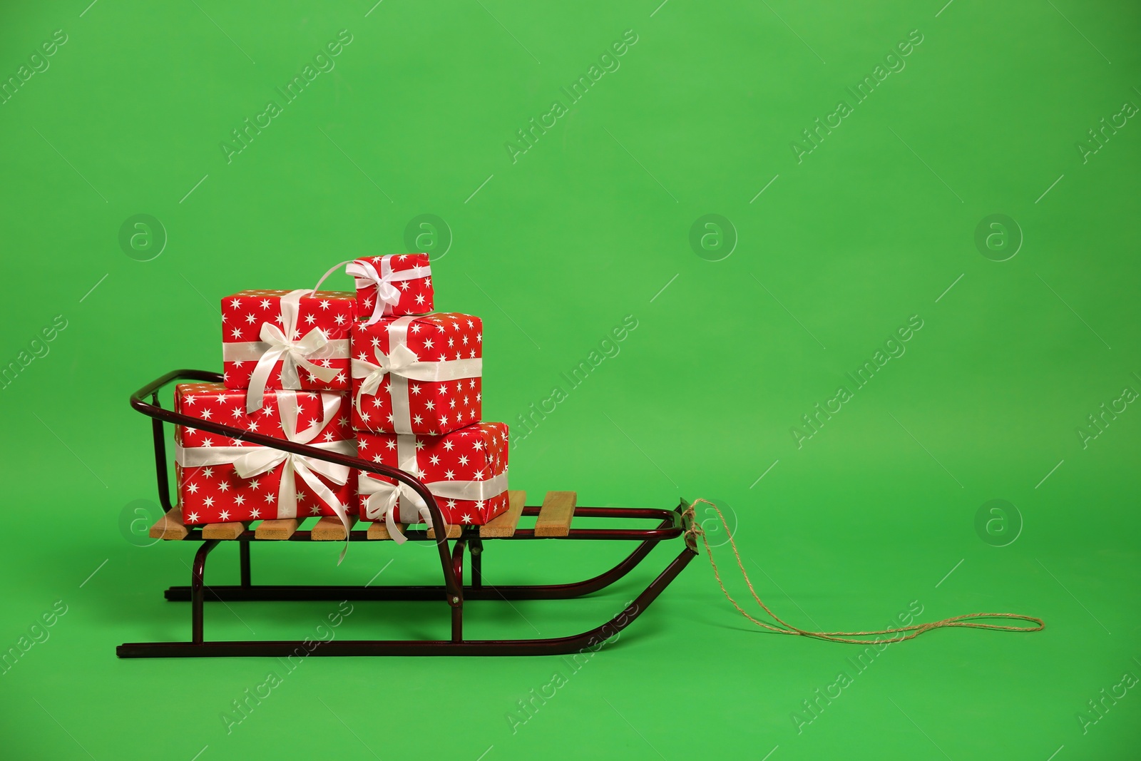 Sleigh with gift boxes on green background. Space for text Photo of Sleigh with gift boxes on green background. Space for text
