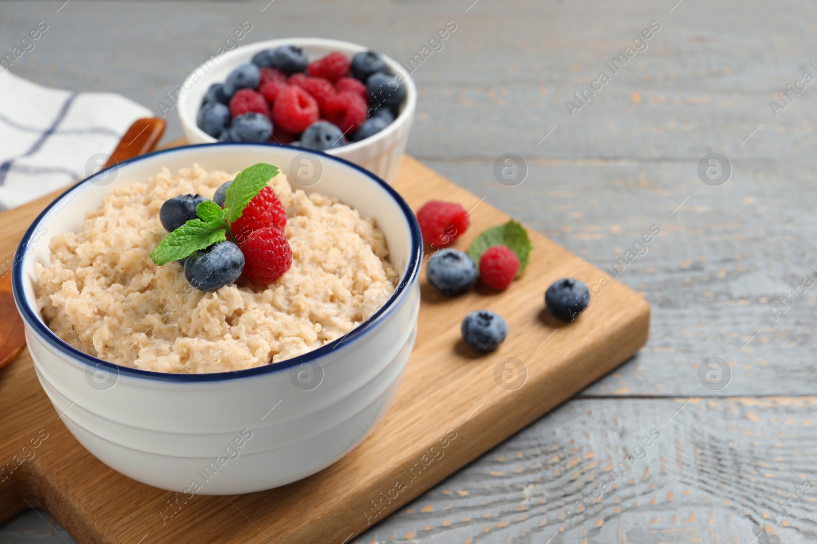 Tasty oatmeal porridge with berries on grey wooden table. Space for text Photo of Tasty oatmeal porridge with berries on grey wooden table. Space for text