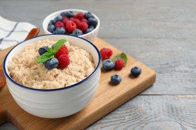 Tasty oatmeal porridge with berries on grey wooden table. Space for text Photo of Tasty oatmeal porridge with berries on grey wooden table. Space for text