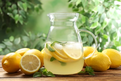 Natural lemonade with mint and fresh fruits on wooden table against blurred background. Summer refreshing drink Photo of Natural lemonade with mint and fresh fruits on wooden table against blurred background. Summer refreshing drink