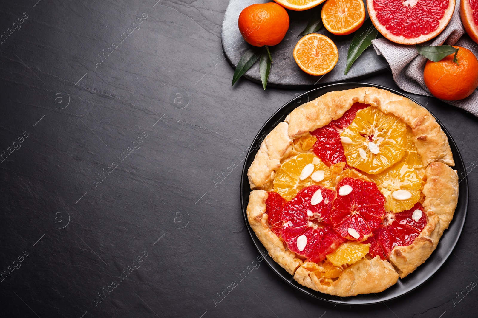 Tasty galette with citrus fruits on dark grey table, flat lay. Space for text Photo of Tasty galette with citrus fruits on dark grey table, flat lay. Space for text