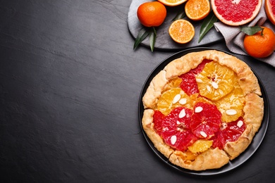 Tasty galette with citrus fruits on dark grey table, flat lay. Space for text Photo of Tasty galette with citrus fruits on dark grey table, flat lay. Space for text