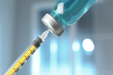 Photo of Filling syringe with medication from vial against blurred background, closeup. Vaccination and immunization