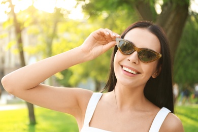 Beautiful young woman wearing stylish sunglasses in park Photo of Beautiful young woman wearing stylish sunglasses in park