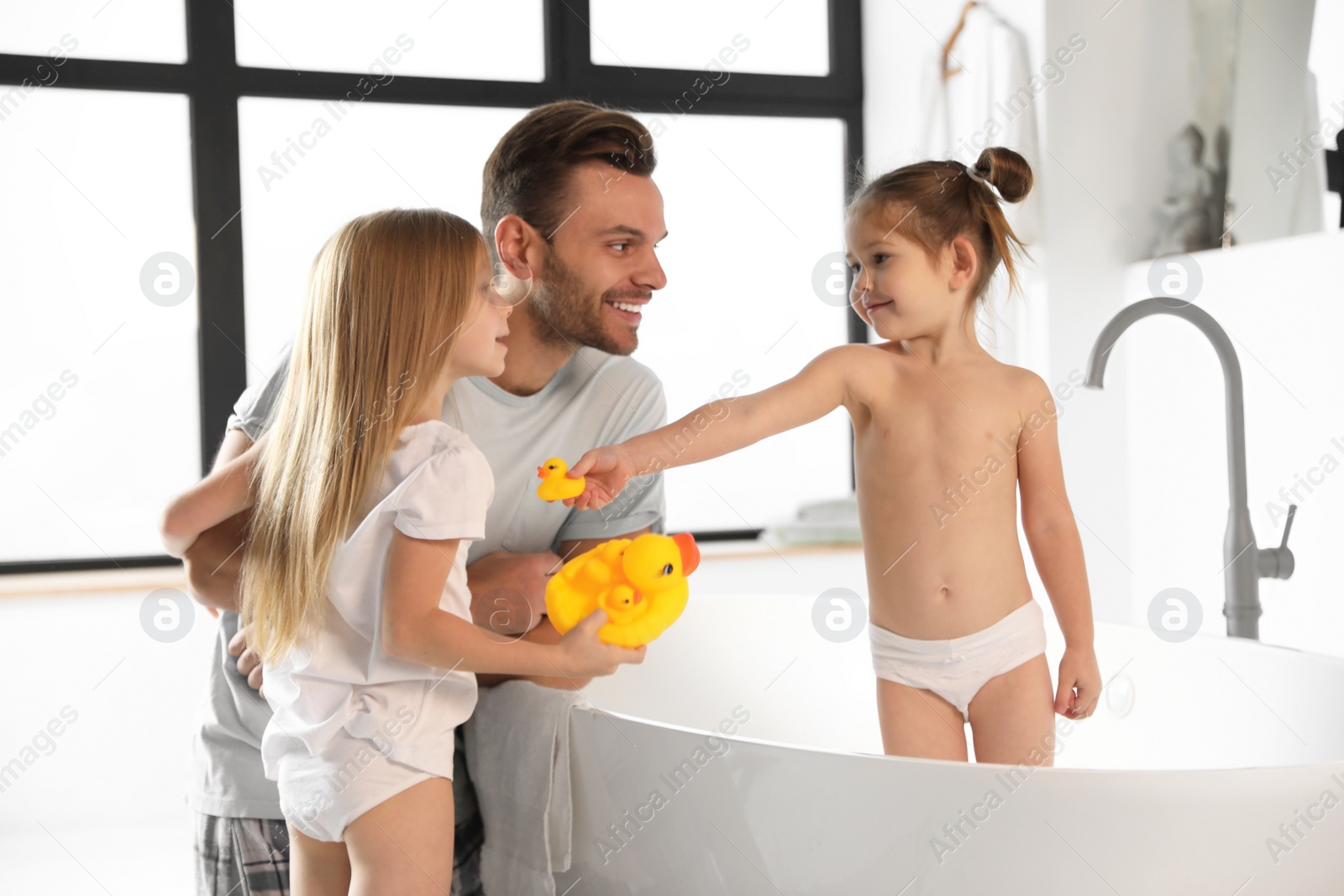 Photo of Young father with little daughters in bathroom