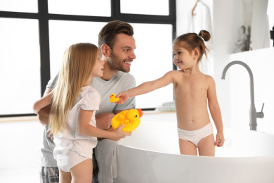 Photo of Young father with little daughters in bathroom