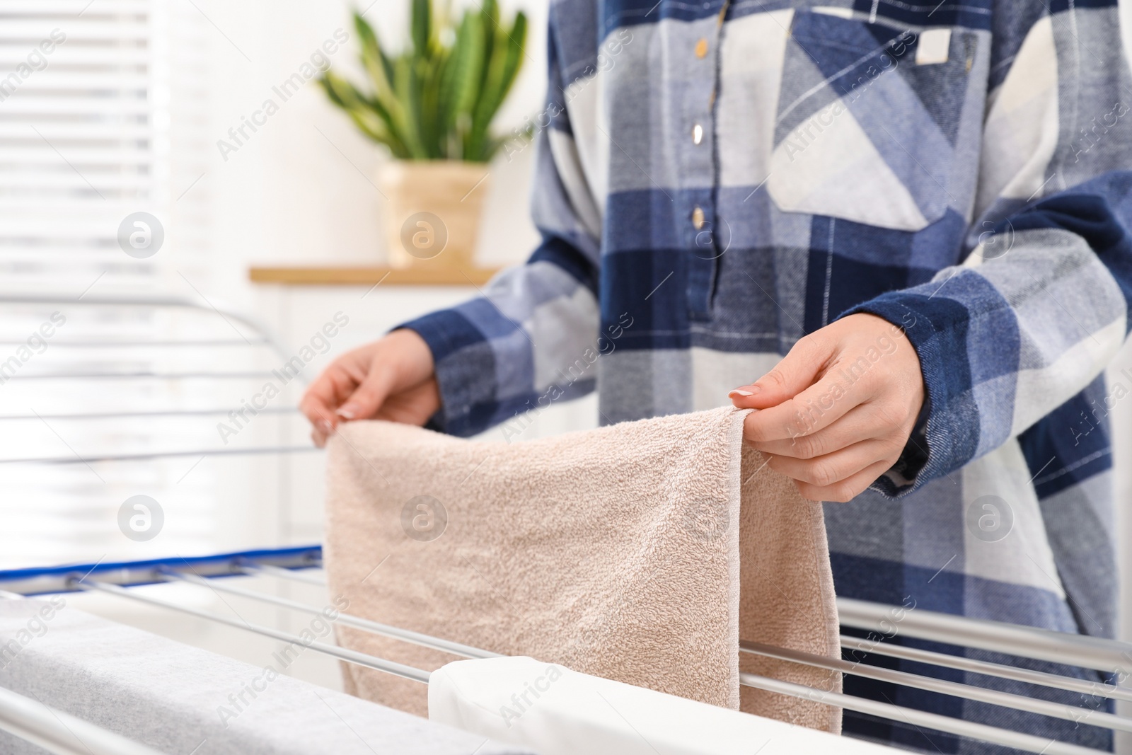 Young woman hanging clean laundry on drying rack at home, closeup Photo of Young woman hanging clean laundry on drying rack at home, closeup