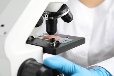 Scientist inspecting meat sample with microscope in laboratory, closeup. Poison detection Photo of Scientist inspecting meat sample with microscope in laboratory, closeup. Poison detection