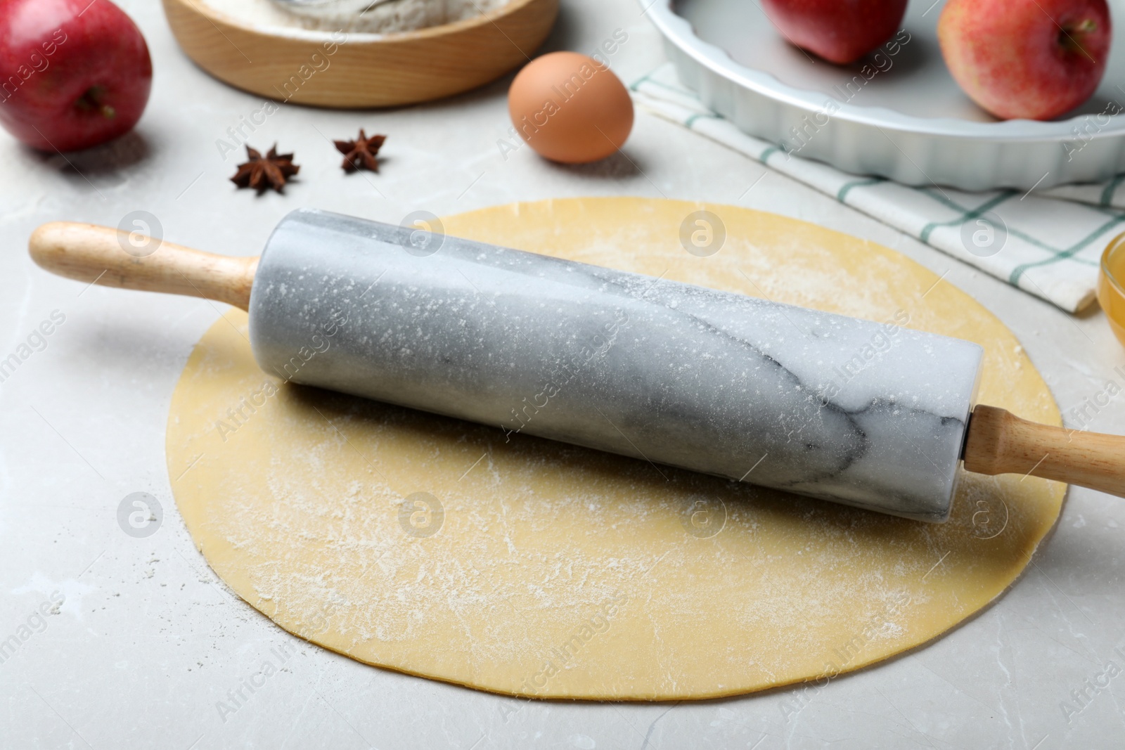 Rolling pin, raw dough and ingredients on light grey table. Baking apple pie Photo of Rolling pin, raw dough and ingredients on light grey table. Baking apple pie