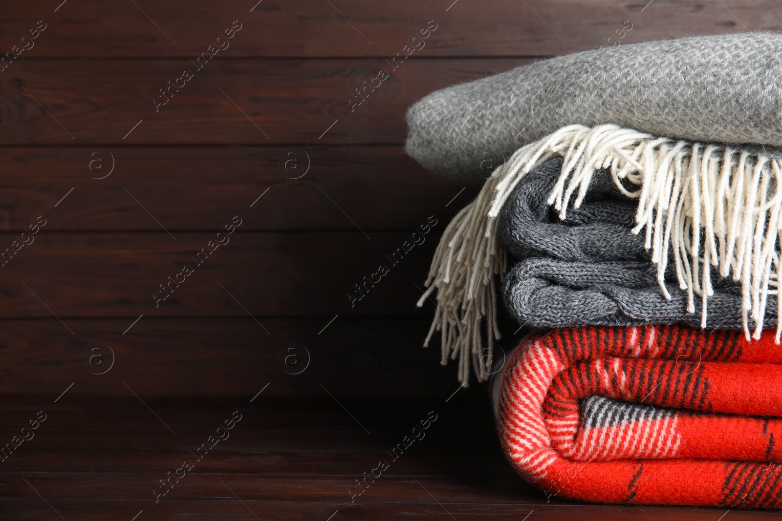 Stack of soft plaids on brown wooden table, closeup. Space for text Photo of Stack of soft plaids on brown wooden table, closeup. Space for text