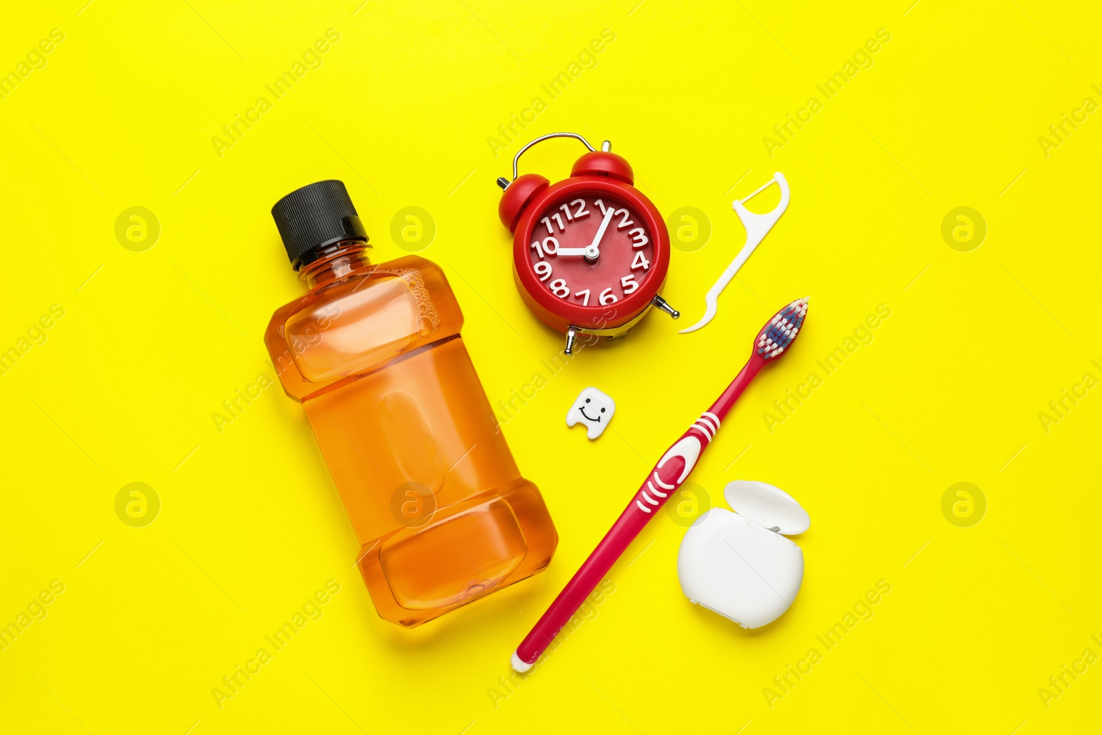Mouthwash, toothbrush, dental floss and alarm clock on yellow background, flat lay Photo of Mouthwash, toothbrush, dental floss and alarm clock on yellow background, flat lay