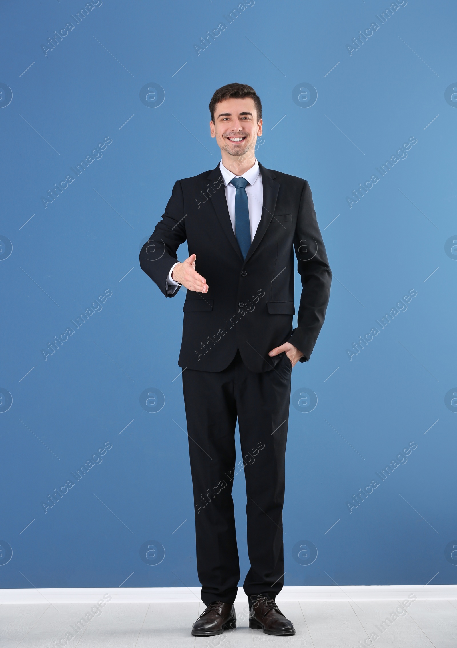 Business trainer reaching out for handshake on color wall background Photo of Business trainer reaching out for handshake on color wall background