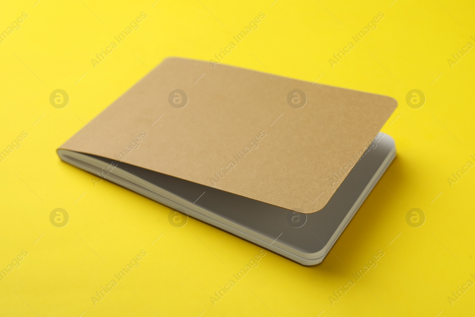 New stylish kraft planner on yellow background Photo of New stylish kraft planner on yellow background