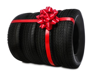 Winter tires with red ribbon on white background Photo of Winter tires with red ribbon on white background