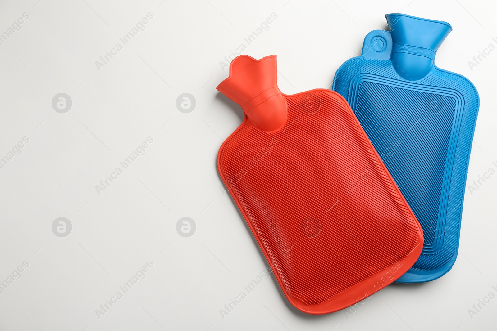 Rubber hot water bottles on white background, top view Photo of Rubber hot water bottles on white background, top view