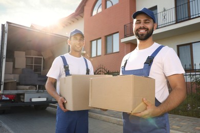 Workers unloading boxes from van outdoors. Moving service Photo of Workers unloading boxes from van outdoors. Moving service