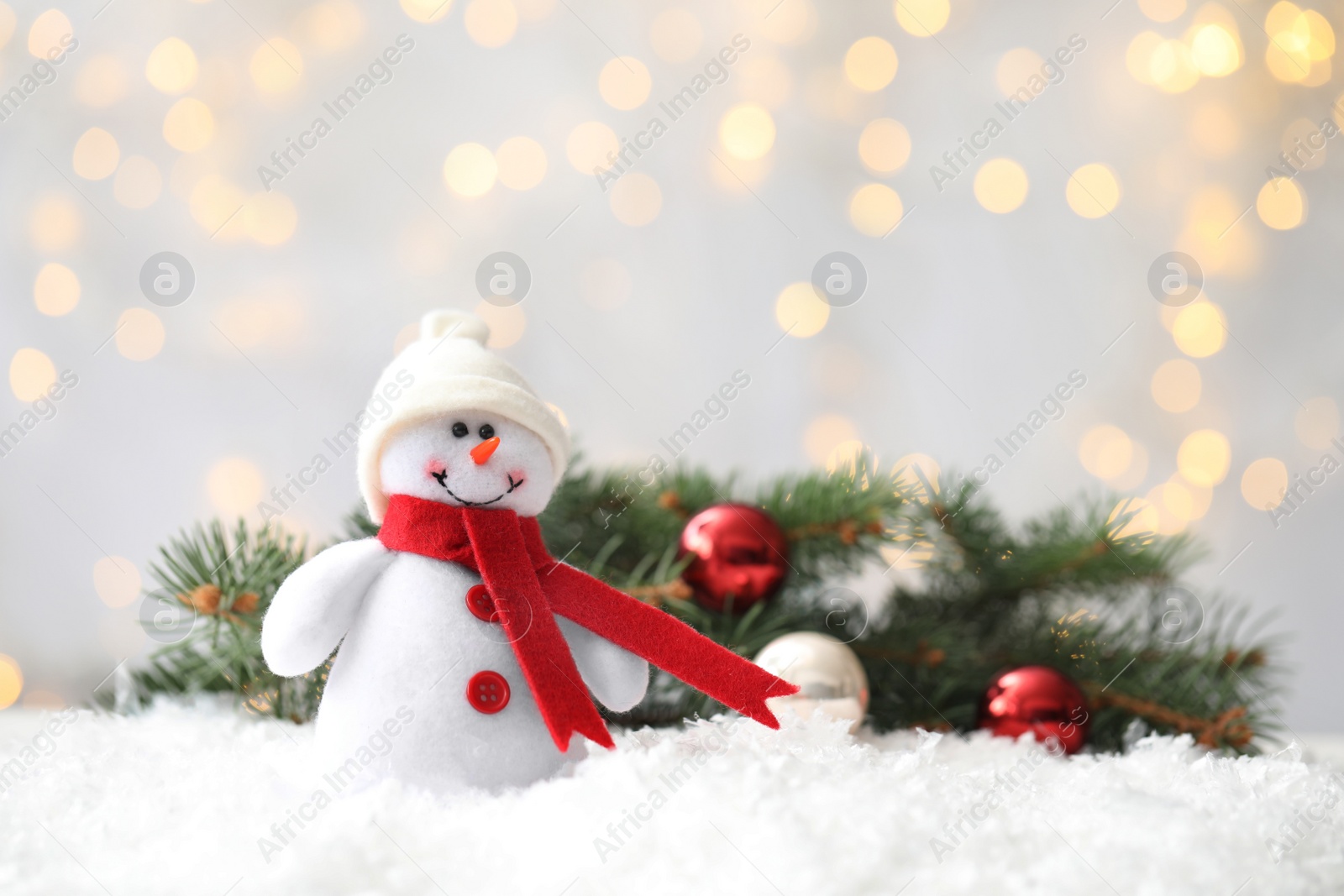 Snowman toy on snow against blurred festive lights, space for text. Christmas decoration Photo of Snowman toy on snow against blurred festive lights, space for text. Christmas decoration