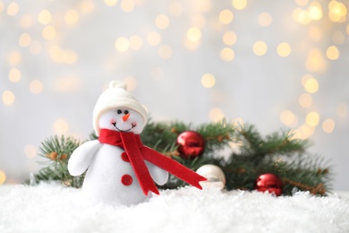 Snowman toy on snow against blurred festive lights, space for text. Christmas decoration Photo of Snowman toy on snow against blurred festive lights, space for text. Christmas decoration