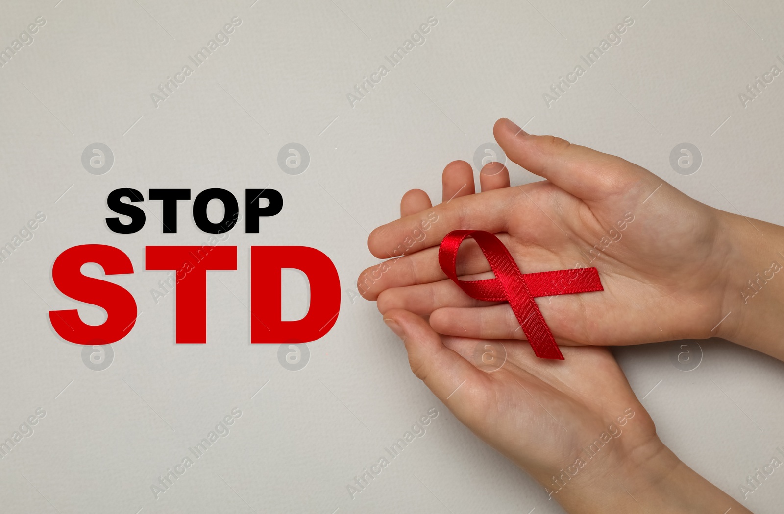 Young woman holding red awareness ribbon on beige background, top view. Stop STD Image of Young woman holding red awareness ribbon on beige background, top view. Stop STD