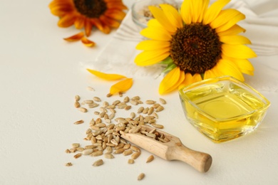 Sunflower oil in glass bowl and seeds on white table Photo of Sunflower oil in glass bowl and seeds on white table