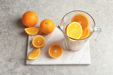 Jug with fresh oranges on marble board. Making juice Photo of Jug with fresh oranges on marble board. Making juice