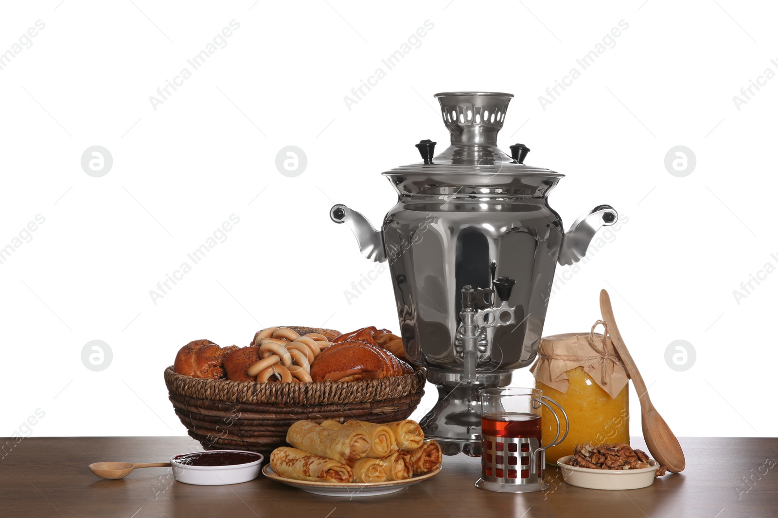 Traditional Russian samovar with treats on wooden table against white background Photo of Traditional Russian samovar with treats on wooden table against white background