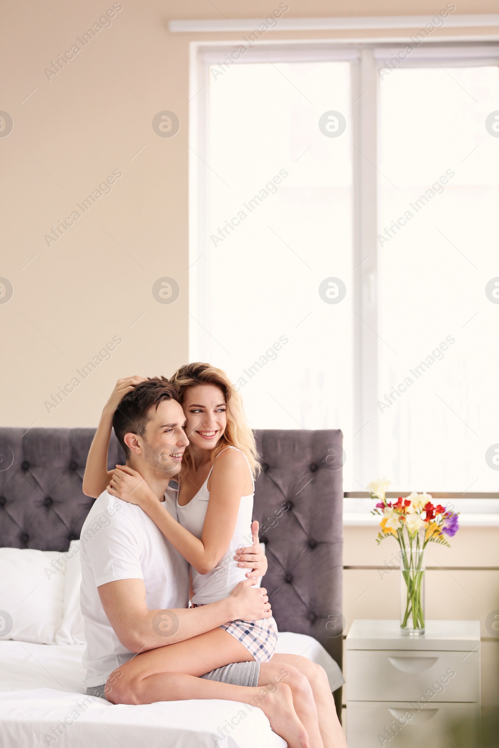 Photo of Happy young couple hugging on bed at home