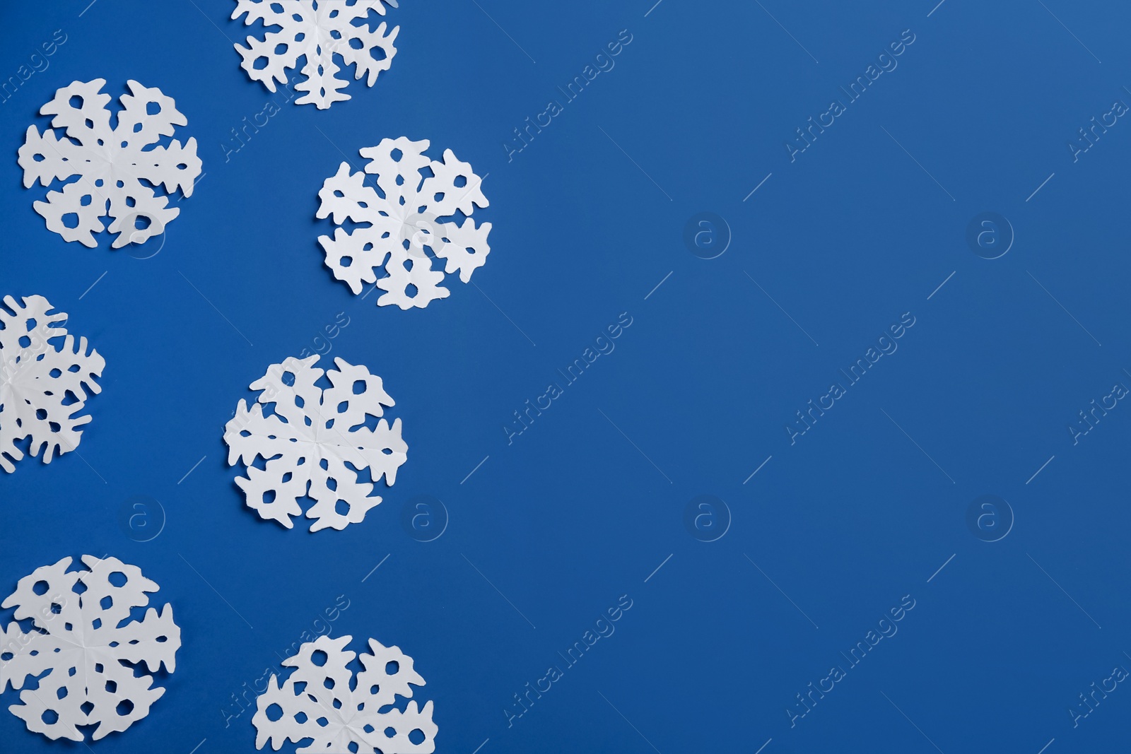 Many paper snowflakes on blue background, flat lay. Space for text Photo of Many paper snowflakes on blue background, flat lay. Space for text