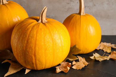 Ripe pumpkins and autumn leaves on black table Photo of Ripe pumpkins and autumn leaves on black table