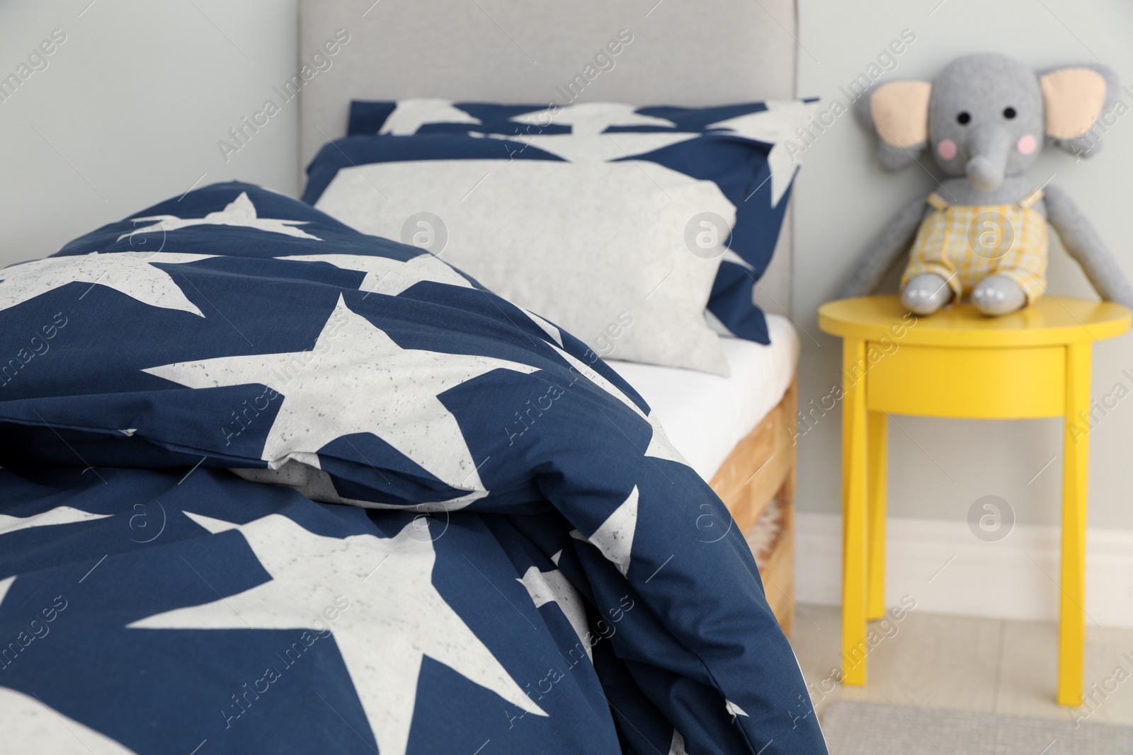 Bed with star patterned linens in child's bedroom. Interior design Photo of Bed with star patterned linens in child's bedroom. Interior design