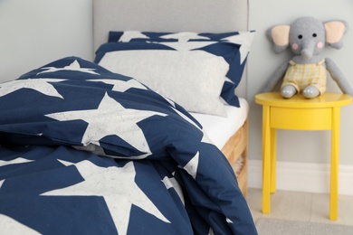 Bed with star patterned linens in child's bedroom. Interior design Photo of Bed with star patterned linens in child's bedroom. Interior design