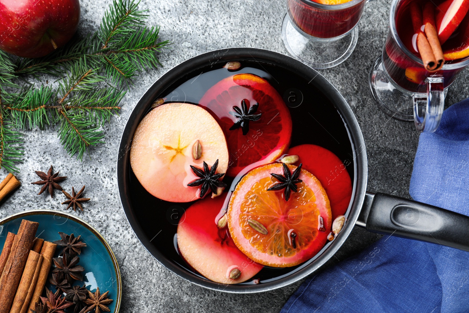 Delicious mulled wine and ingredients on grey table, flat lay Photo of Delicious mulled wine and ingredients on grey table, flat lay