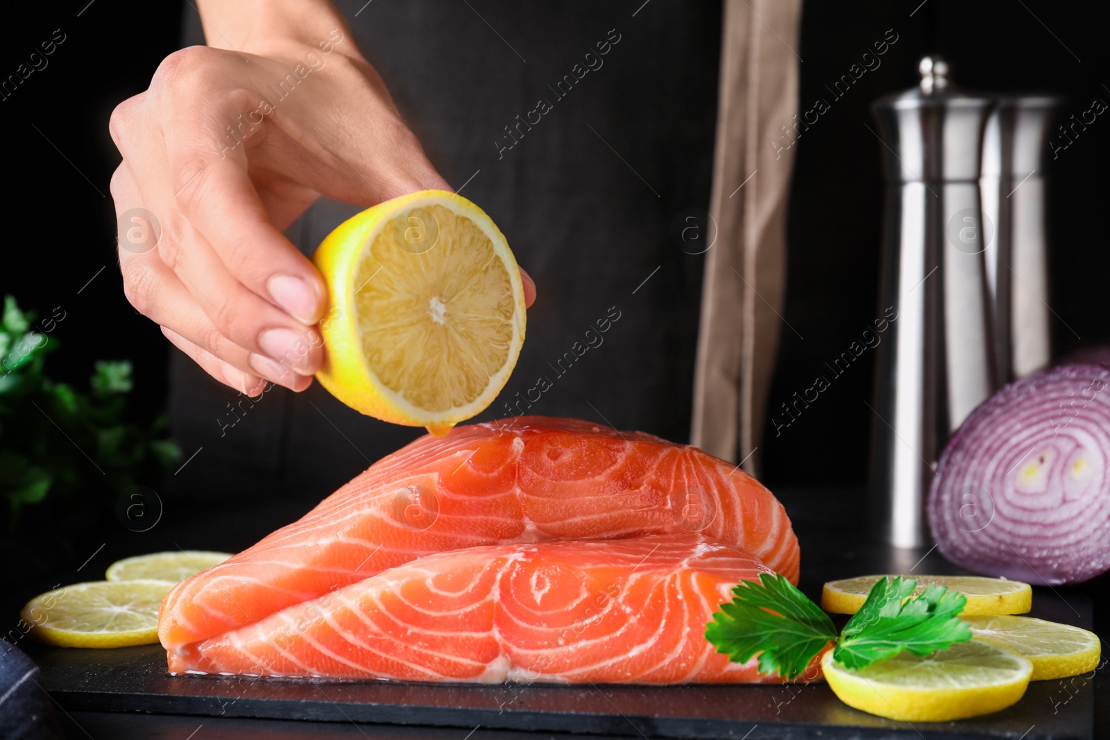 Woman squeezing lemon onto fresh raw salmon at table, closeup. Fish delicacy Photo of Woman squeezing lemon onto fresh raw salmon at table, closeup. Fish delicacy
