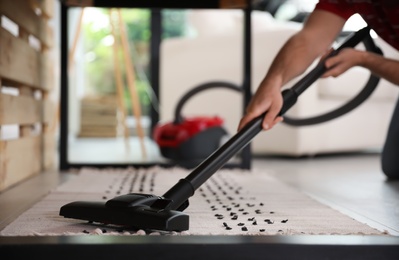 Young man using vacuum cleaner at home, closeup Photo of Young man using vacuum cleaner at home, closeup
